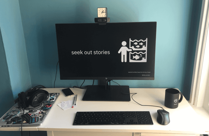 A home office desk, with a computer showing a slide with a large icon of a person next to an aquarium